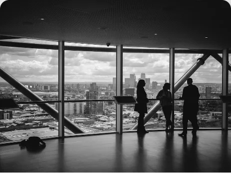 Silhouetted business team looking over a city from a high-rise office